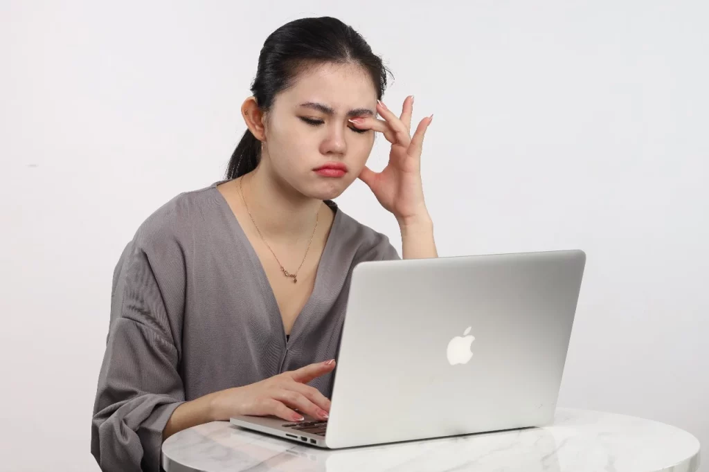 Mata Sering Berkedip: Seseorang sedang mengucek matanya di depan laptop.